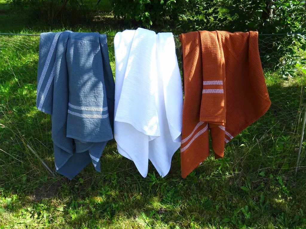 Auf dem Foto sind die Organic Rib Bath Towels Badetücher von der Weberei MUNGO aus Südafrika gewebt aus reiner Bio Baumwolle in den Farben Dunkelgraublau, Weiß, Rostbraun.