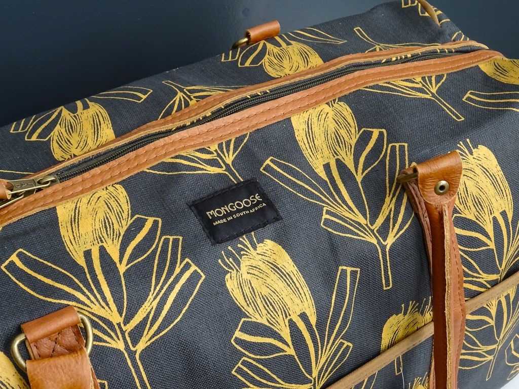 Kleine Reisetasche Weekend Bag von Mongoose handcrafted Südafrika aus dunkelgrauem Baumwollstoff bedruckt mit der Sugarbush Protea in Senfgelb mit Ledergriffen in Hellbraun und Reißverschluss